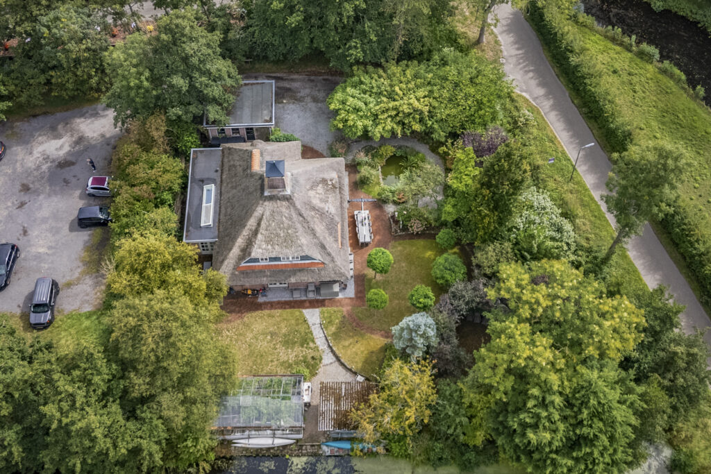 Aerial view of house with lush green surroundings.