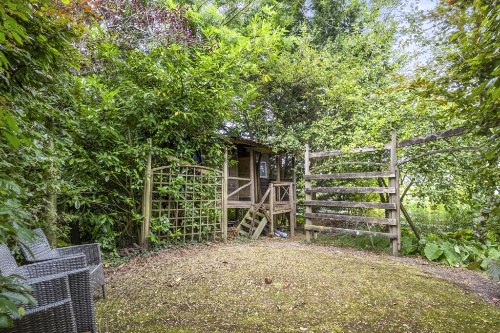 Wooden treehouse surrounded by lush green foliage.