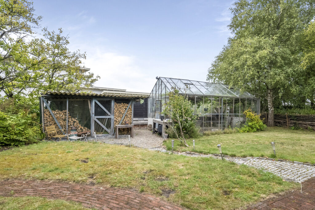 Garden with wood shed and glass greenhouse.