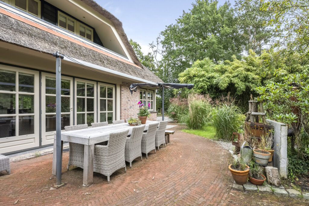 Cozy patio with wicker furniture and lush greenery.