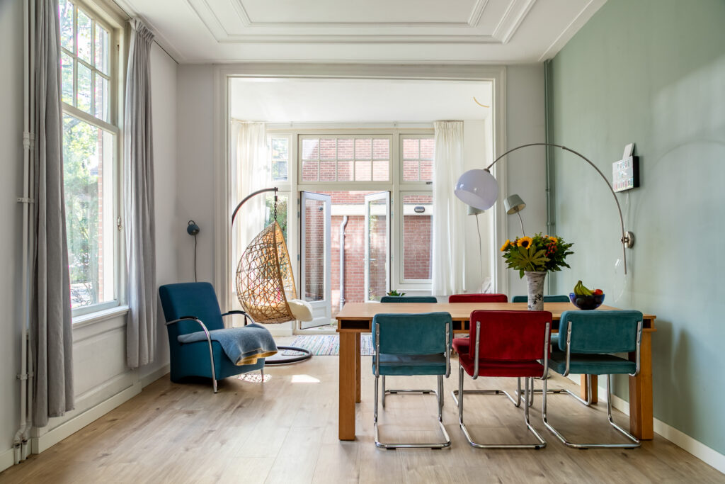 Modern dining room with colorful chairs and hanging chair.