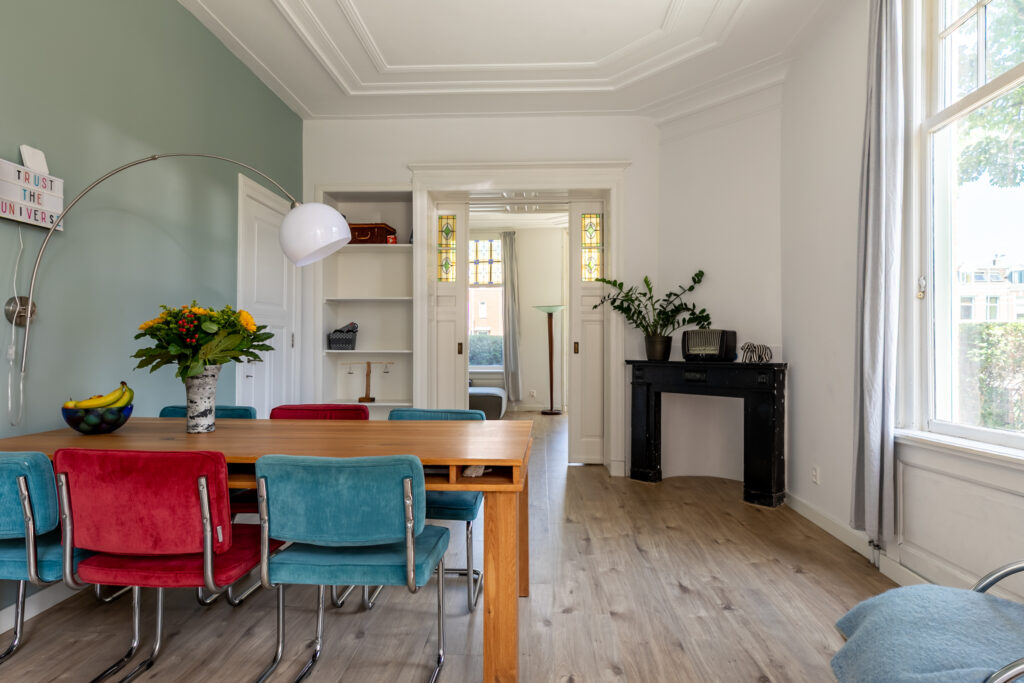 Bright dining room with colorful chairs and wood table.
