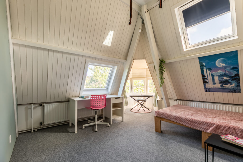 Cozy attic room with desk and bed view.