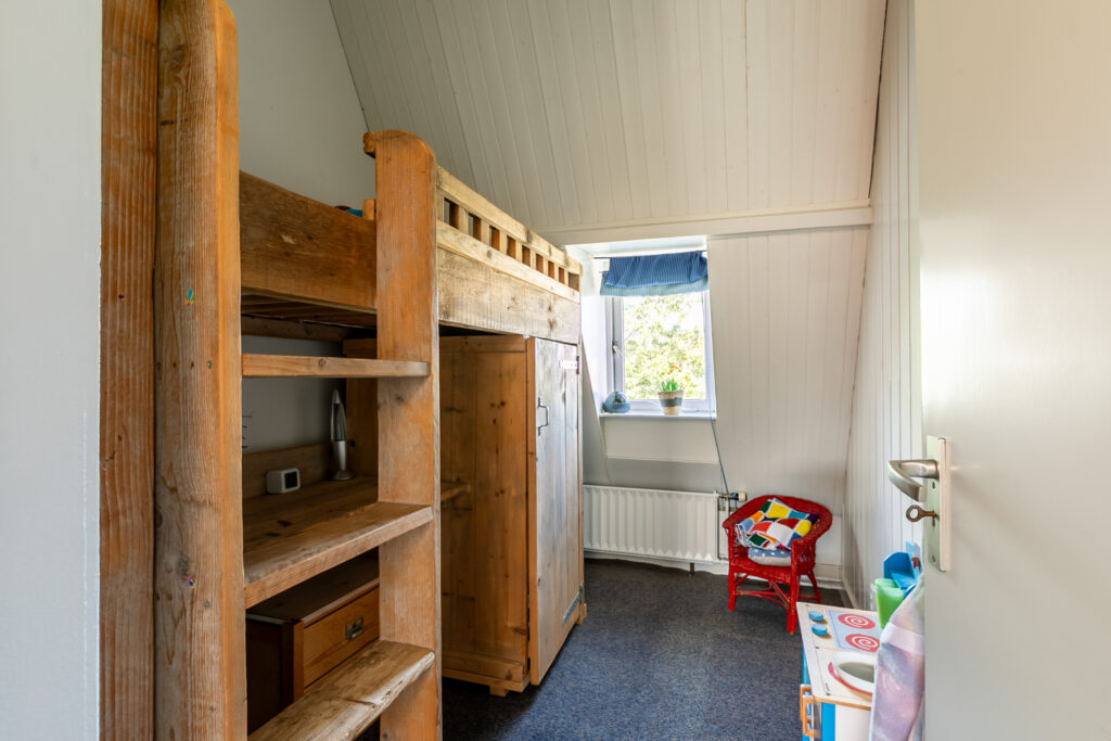 Cozy child’s room with wooden furniture and window.