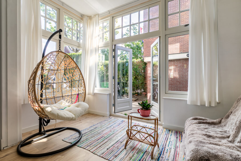 Cozy sunlit room with hanging chair and table.