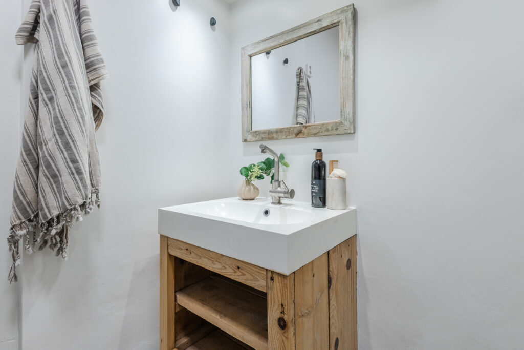 Minimalist bathroom sink with wooden cabinet and mirror.