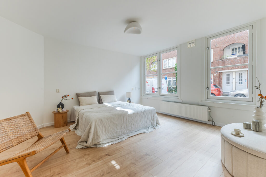 Bright bedroom with bed and large windows.
