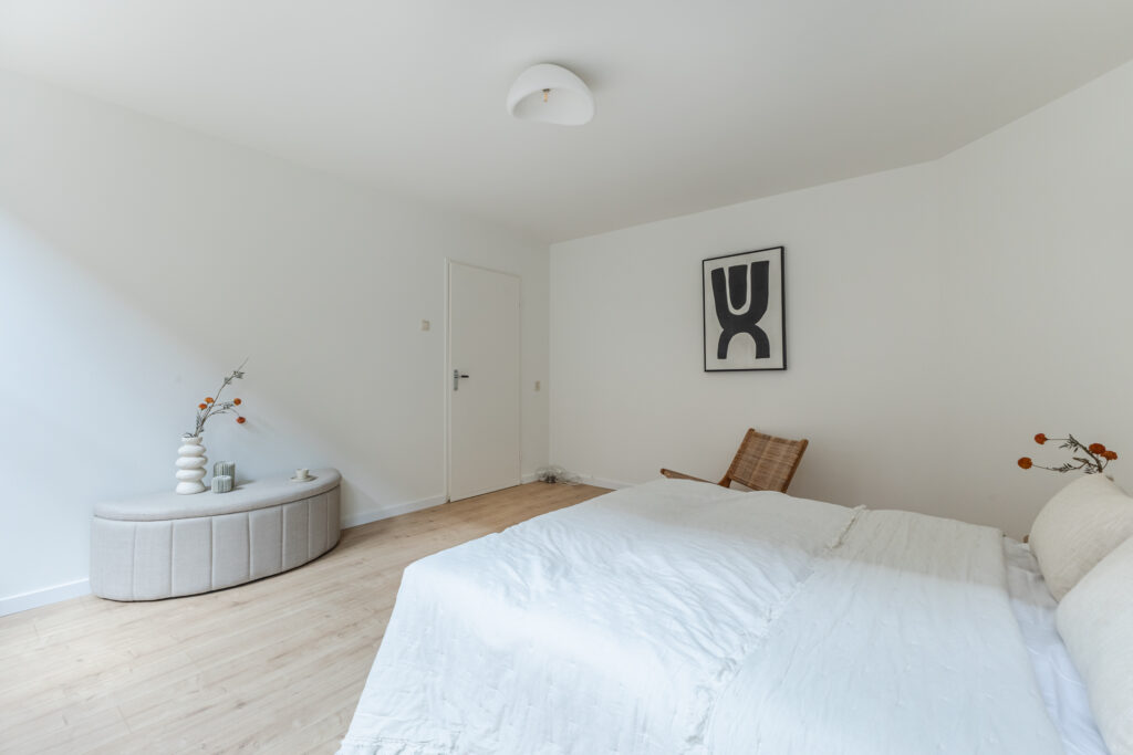 Minimalist bedroom with abstract art and white decor.