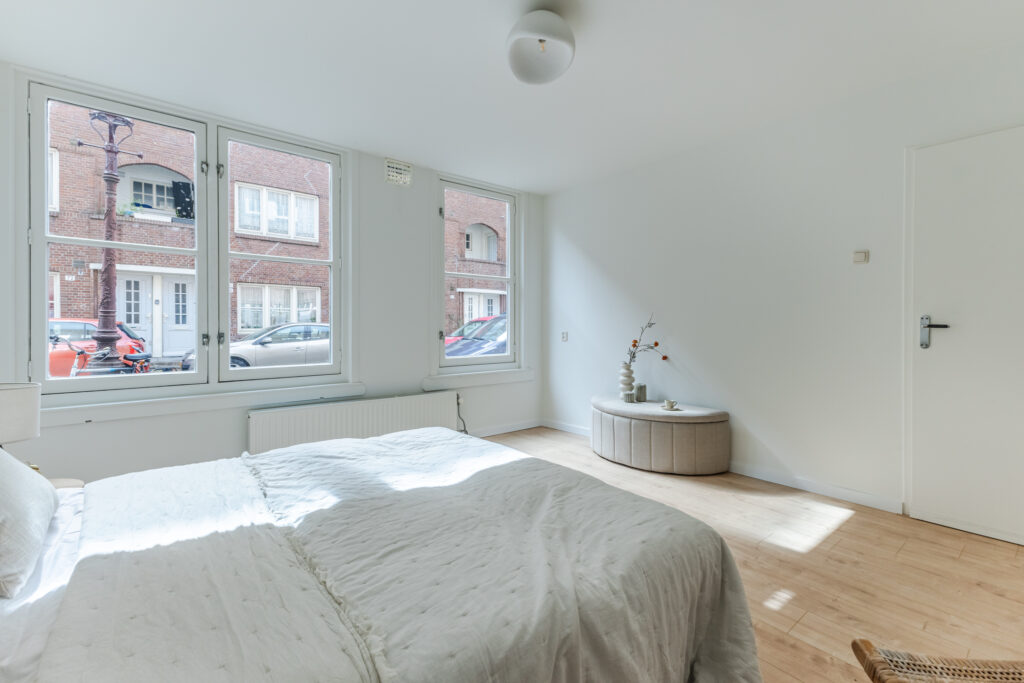 Bright bedroom with large windows and minimalist decor.