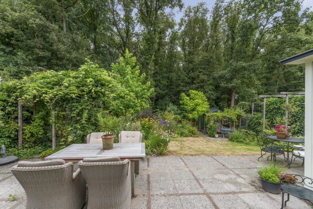 Lush backyard garden with patio furniture and greenery.