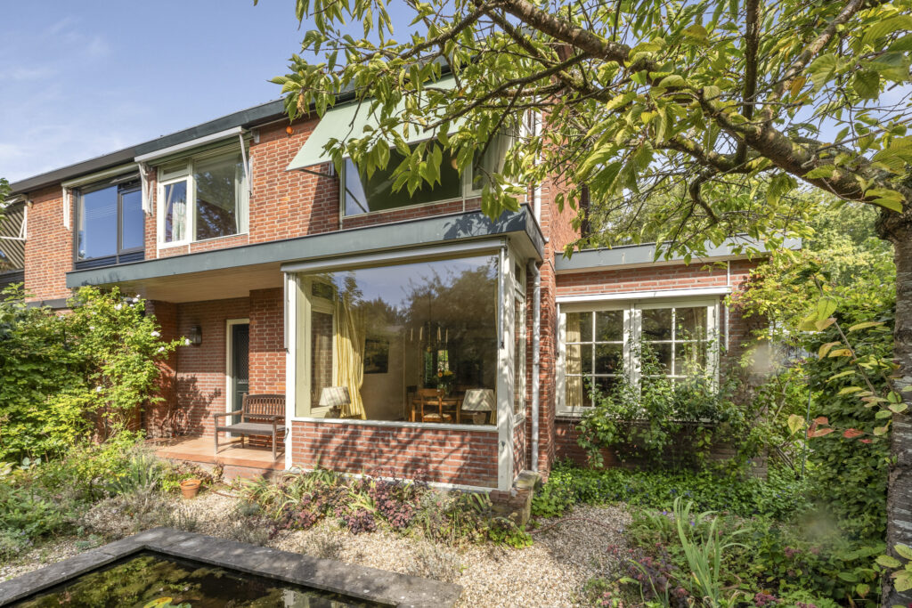 Charming brick house with garden and large windows.