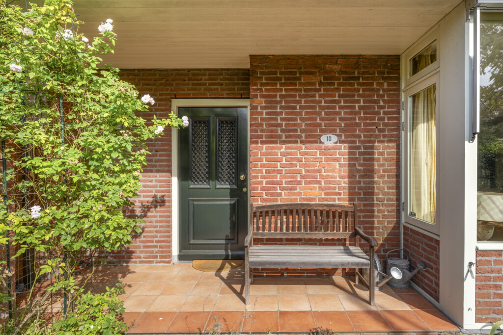 Front porch with wooden bench and green door.