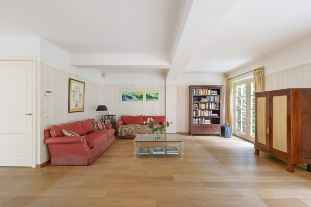 Spacious living room with red sofas and bookshelf.
