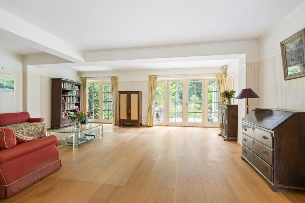 Spacious living room with large windows and bookshelf.