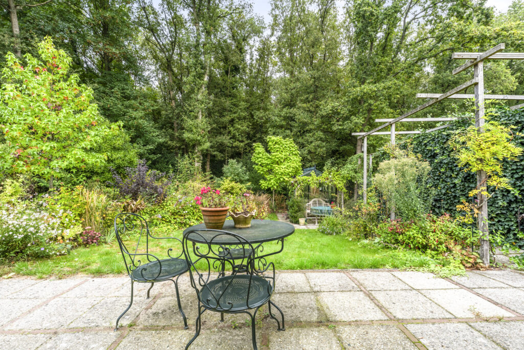 Lush garden with table and chairs in foreground.