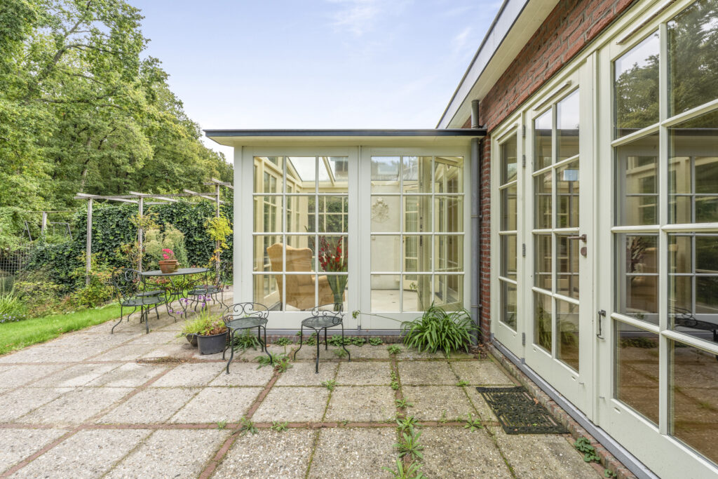 Sunlit patio with garden furniture and glass doors.