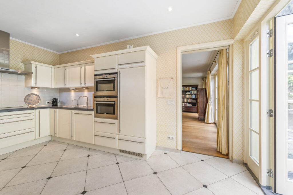 Spacious kitchen with white cabinets and double ovens.