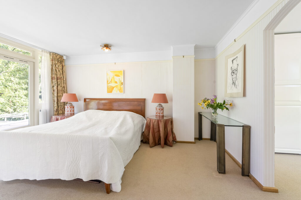 Bright bedroom with bed, lamps, and wall art.
