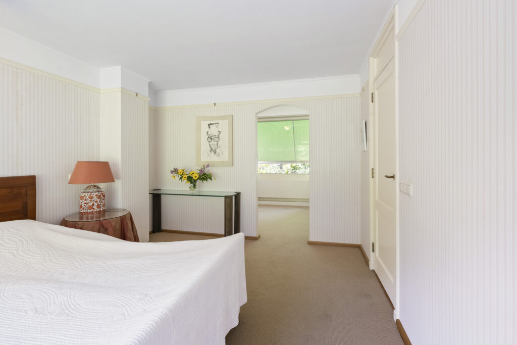 Spacious bedroom with artwork and flowers on table.