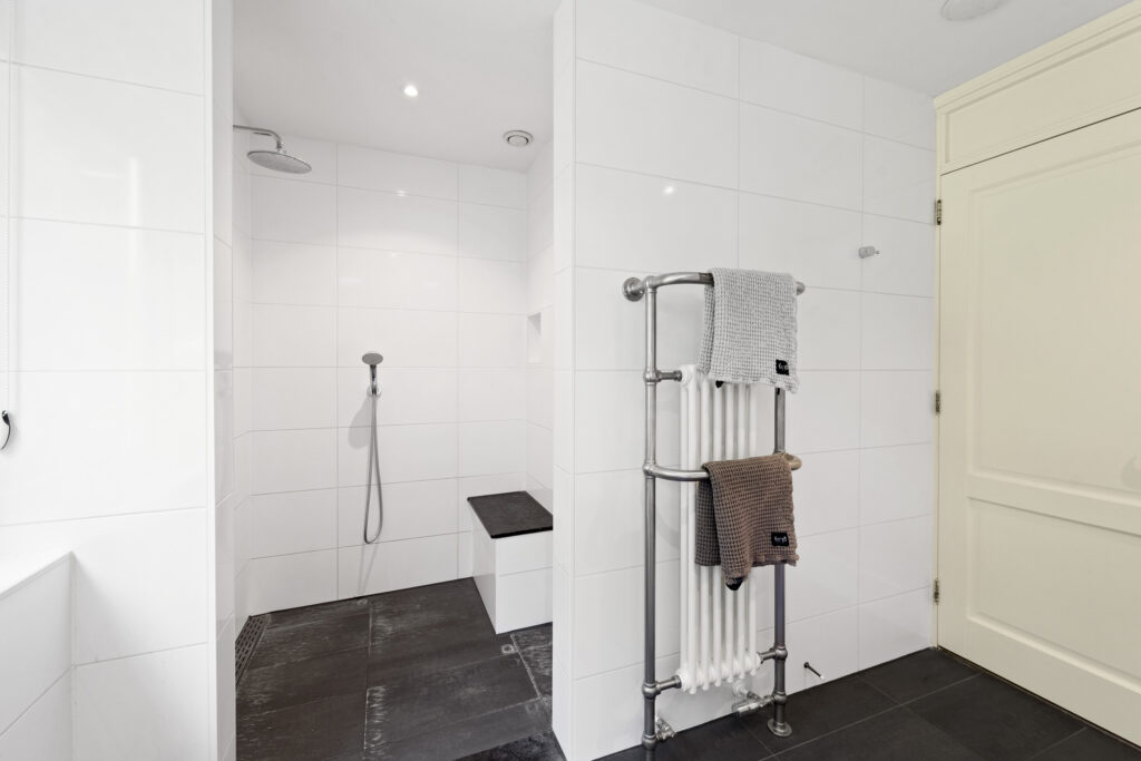 Modern bathroom with open shower and towel rack.