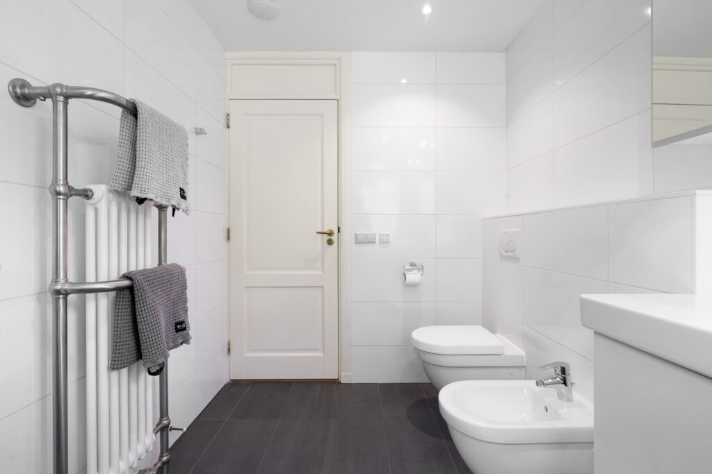 Minimalist bathroom with towel radiator and bidet.