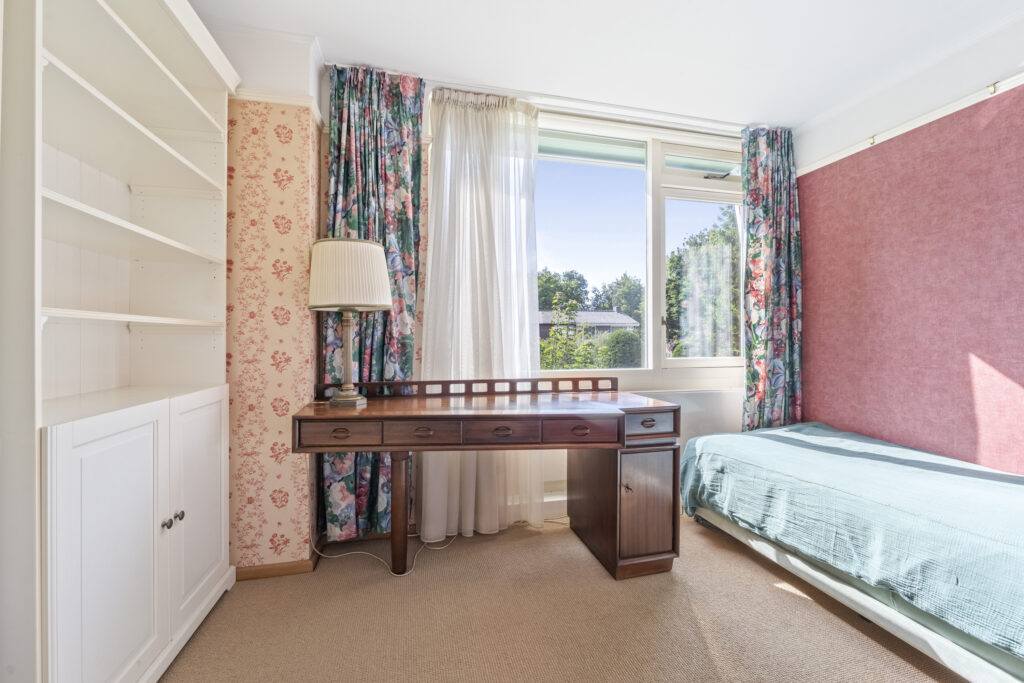 Bedroom with desk, floral curtains, and bookshelf