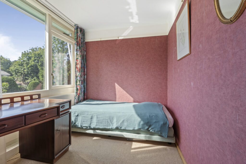 Cozy bedroom with single bed, window, and desk.