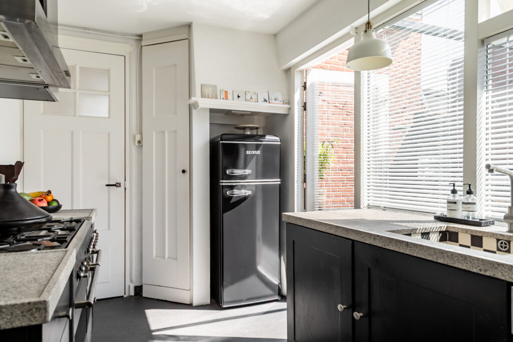 Modern kitchen with black fridge and sunlight.