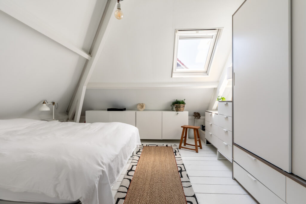 Cozy loft bedroom with skylight and white decor.