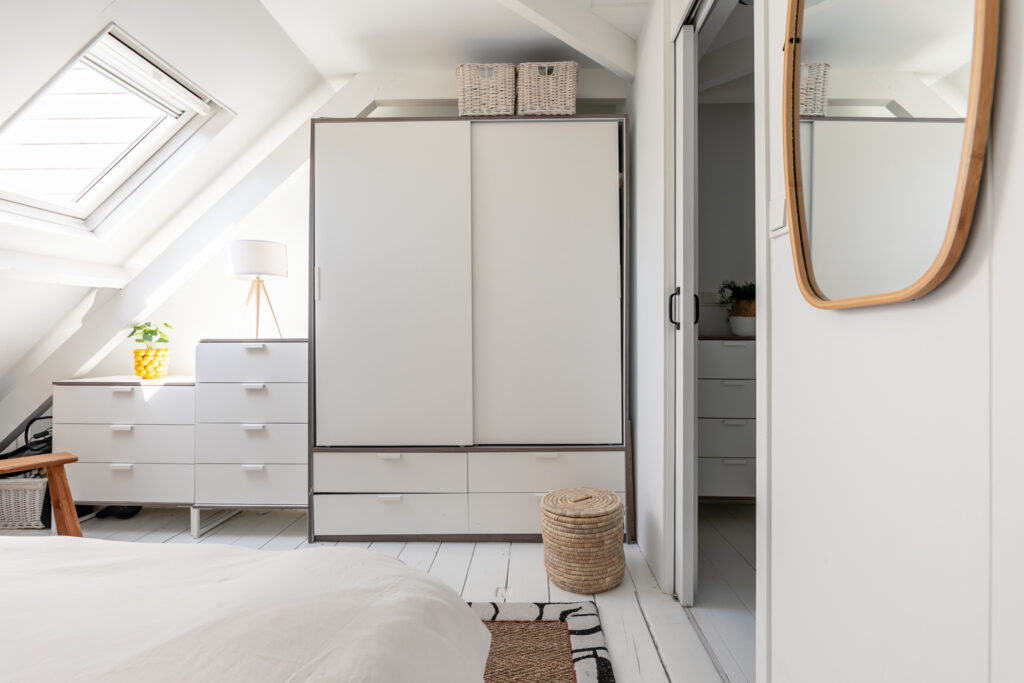 Bright bedroom with modern white furniture and mirror.