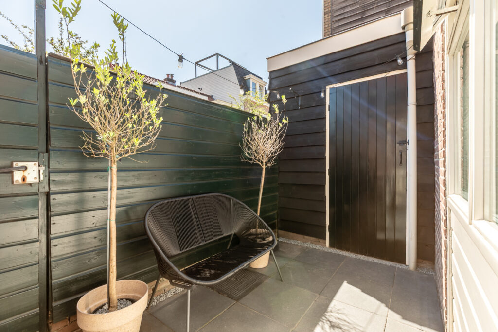 Cozy patio with plants and black bench chair.