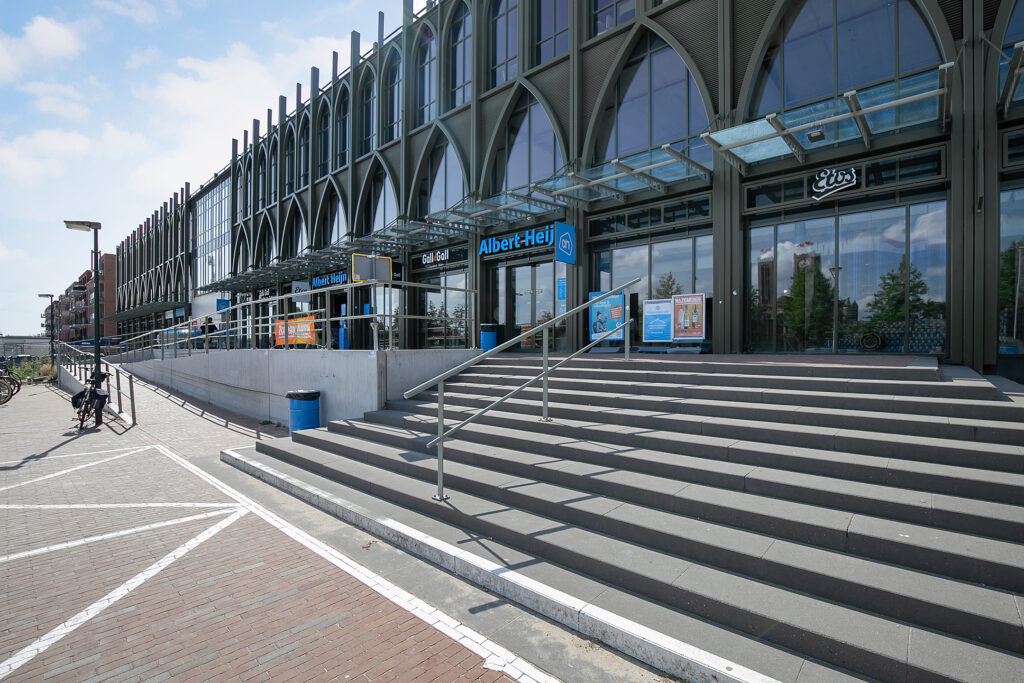 Supermarket entrance with glass facade and wide steps.