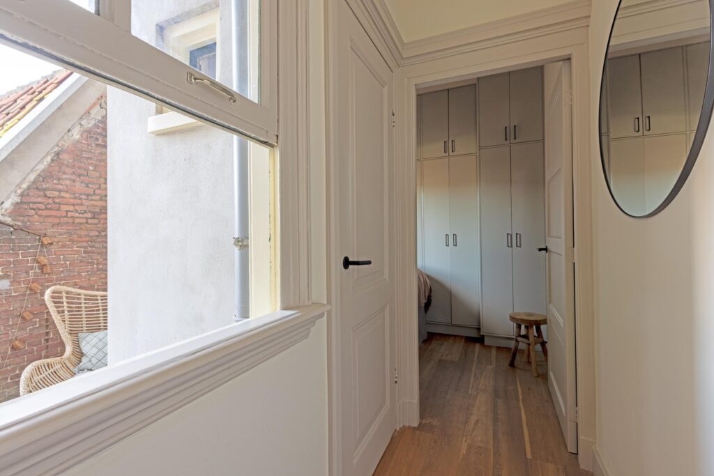 Narrow hallway with storage cabinets and wooden stool.