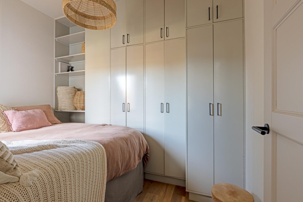 Cozy bedroom with white closet and shelves.
