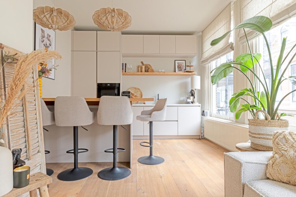 Modern kitchen with barstools and potted plant.