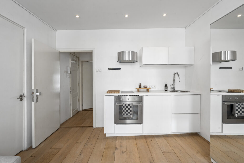Modern white kitchen with wooden flooring.