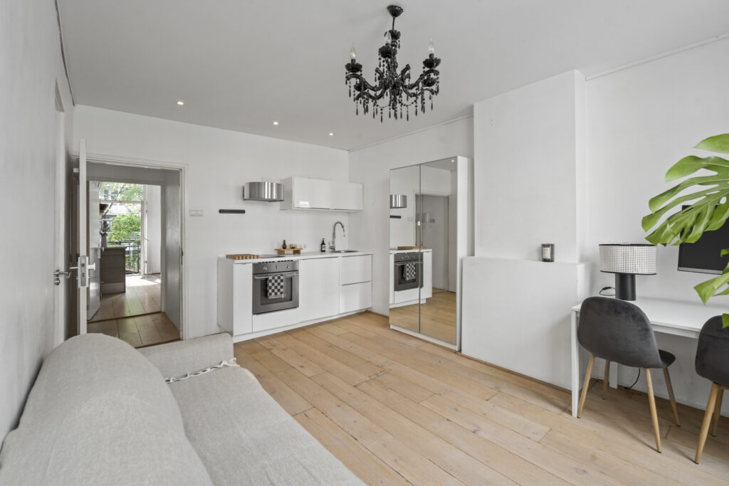 Modern open-plan kitchen with white decor and chandelier.