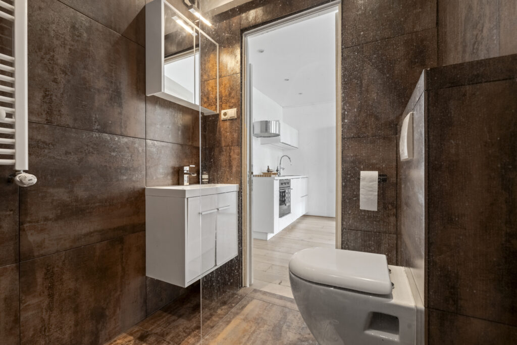 Modern bathroom with brown tiles and white fixtures.
