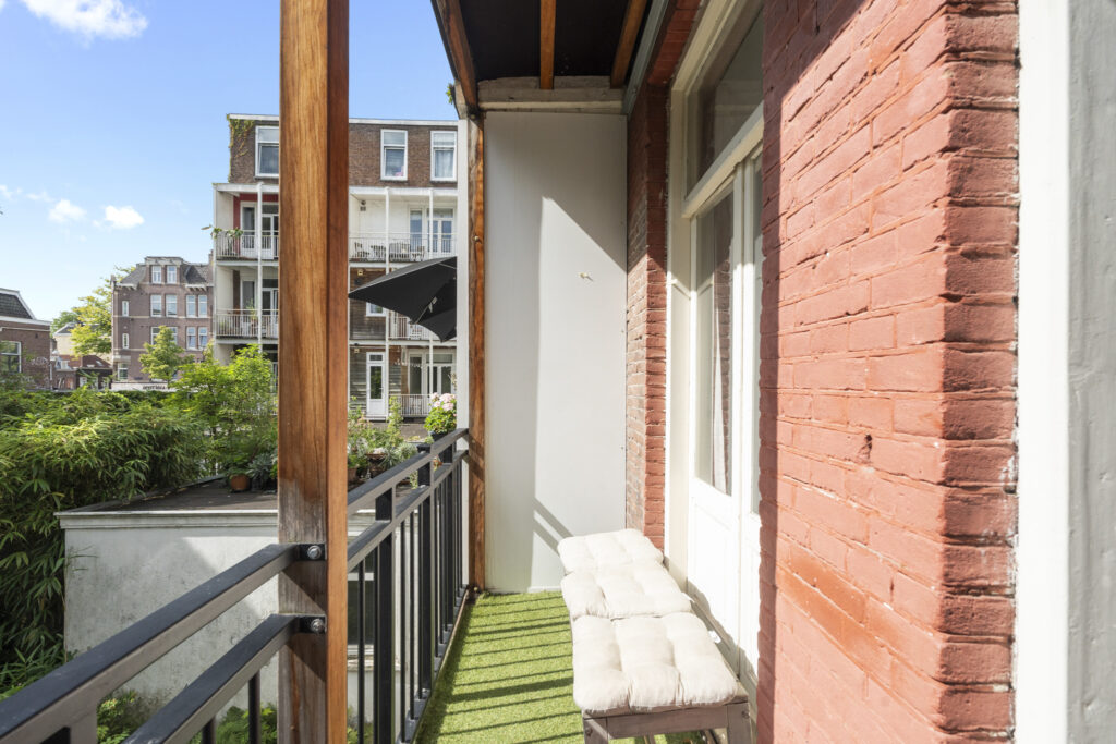 Sunny balcony with green plants and cushioned bench