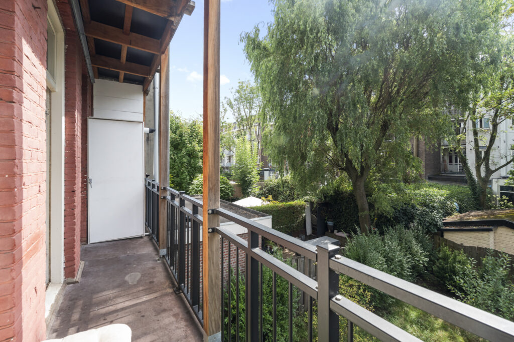 Balcony overlooking a lush garden with trees.