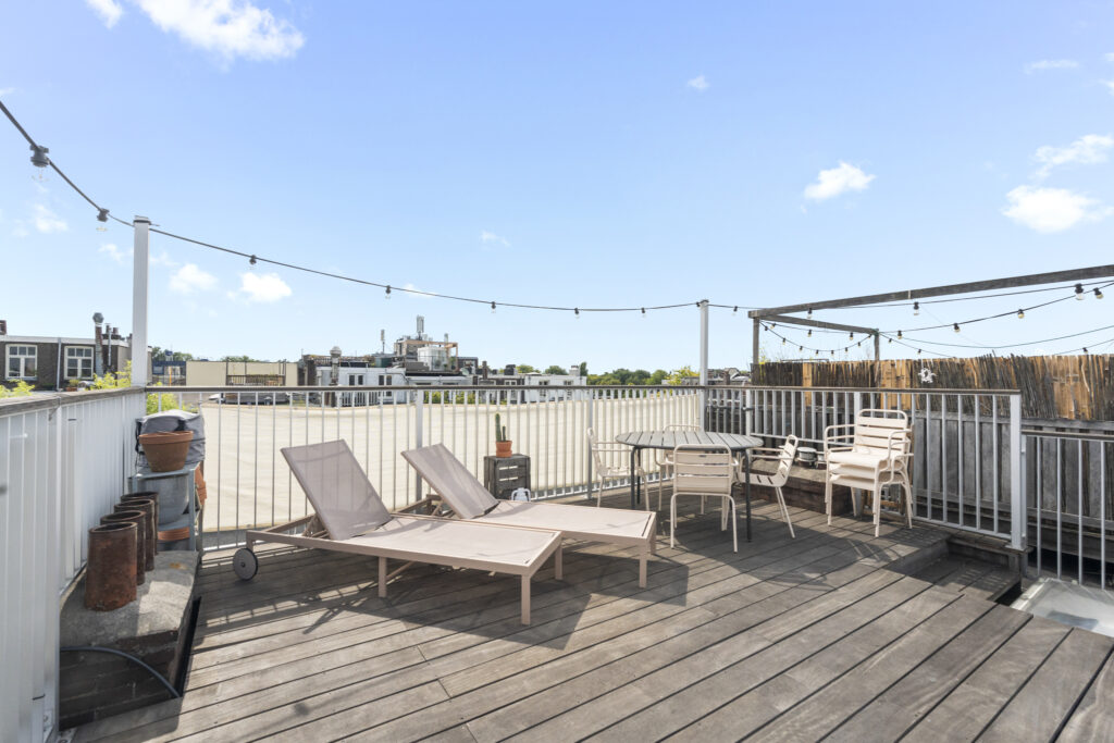 Rooftop patio with lounge chairs and table set.