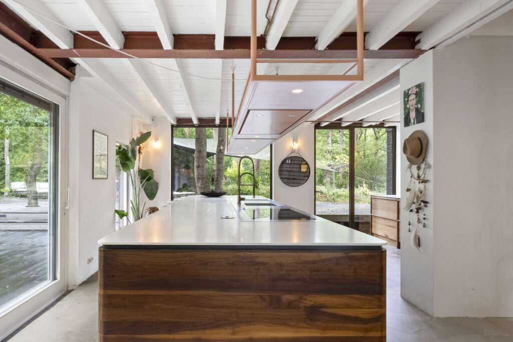 Modern kitchen with forest view and large windows.