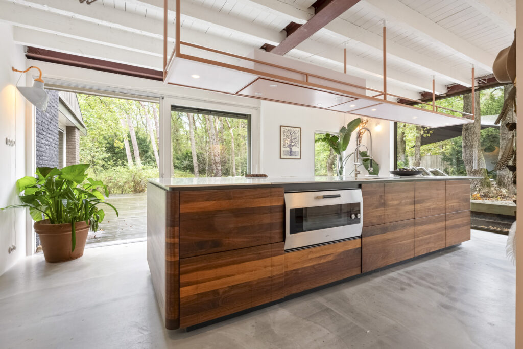 Modern kitchen with wooden cabinets and garden view.