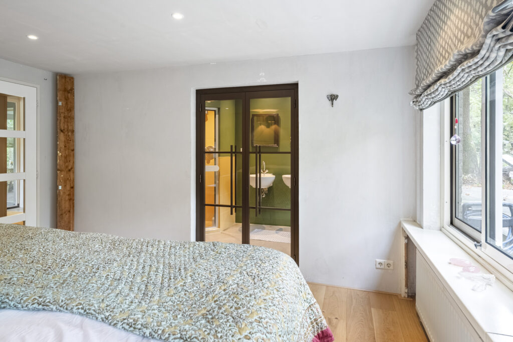 Cozy bedroom with view into bathroom through glass doors.