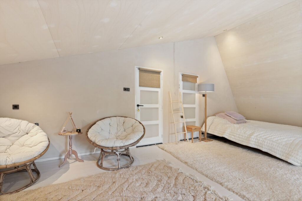 Cozy attic bedroom with papasan chairs and bed.