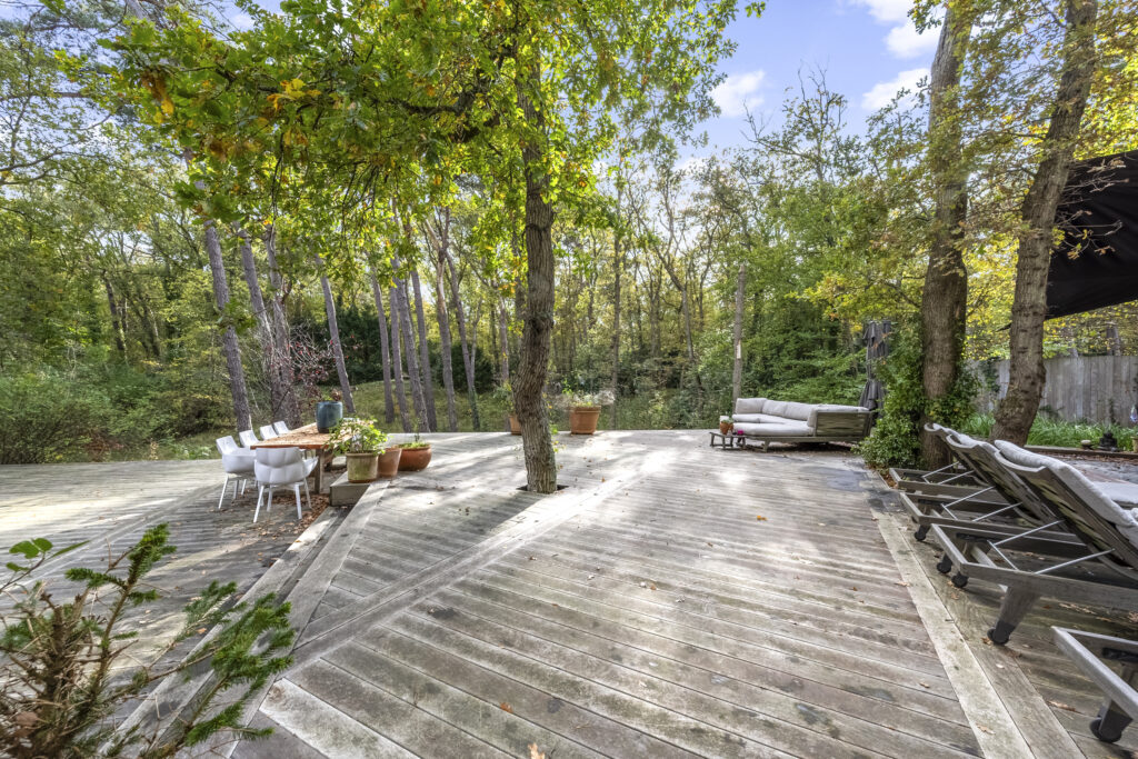 Spacious wooden deck in forest setting with furniture