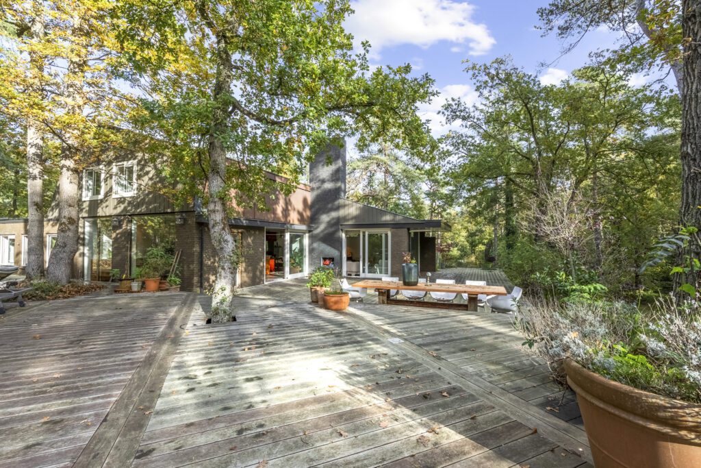 Modern house with spacious wooden deck in forest.