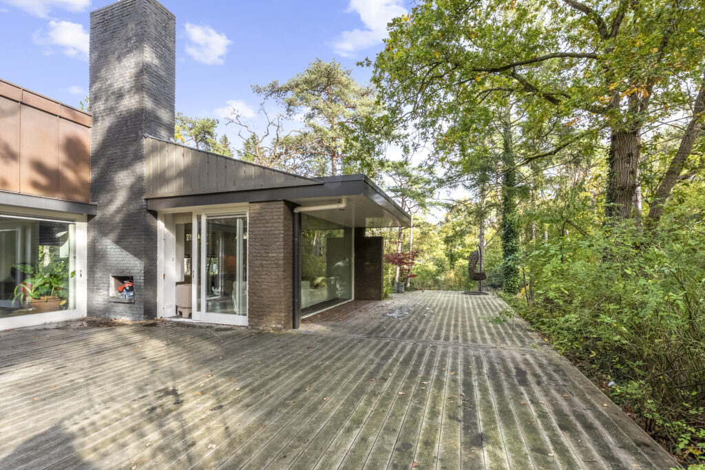 Modern home with spacious wooden deck and trees