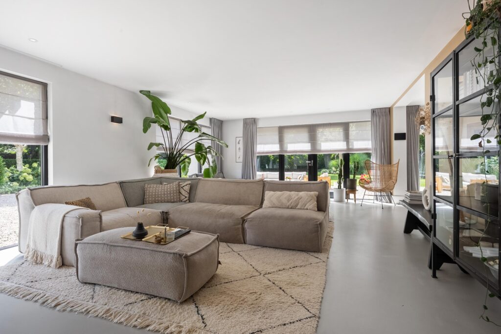 Modern living room with large beige sofa and plants.