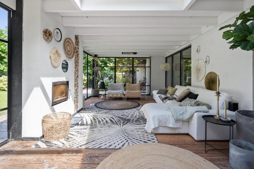 Modern sunroom with wicker decor and large windows.